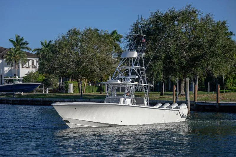 The Image of 2022 SeaVee 390Z boat on a calm waterway, surrounded by trees and docks. - 1