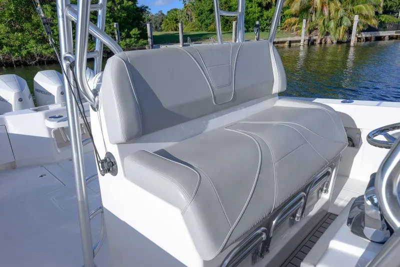 Slide: The Image of 2022 SeaVee 390Z boat with gray cushioned seating, docked by lush greenery. - 14