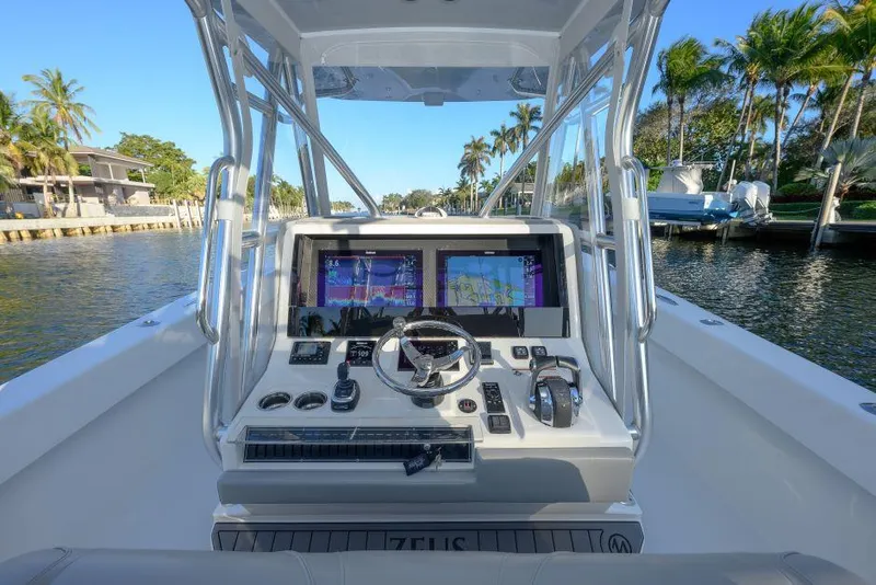 Slide: The Image of 2022 SeaVee 390Z boat helm with dual screens, steering wheel, and controls on a sunny day. - 15