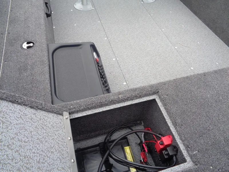 Slide: The Image of 2025 Lund 1650 Rebel XL Tiller interior, featuring storage compartment and battery setup. - 10