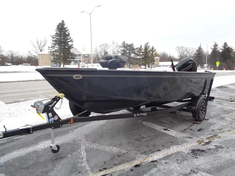 Slide: The Image of 2025 Lund 1650 Rebel XL Tiller boat on trailer in snowy parking lot. - 2