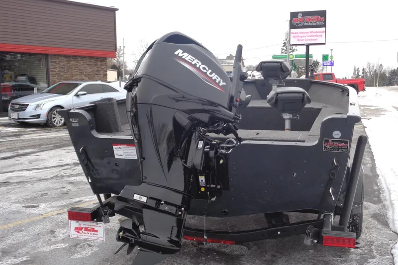 Slide: The Image of 2025 Lund 1650 Rebel XL Tiller boat with Mercury outboard motor, parked on snowy pavement. - 21