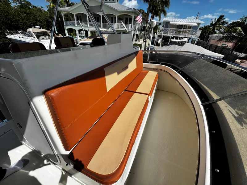 Slide: The Image of 1991 Tiara Yachts 3600 Convertible boat with orange and beige seating, docked near waterfront homes. - 18