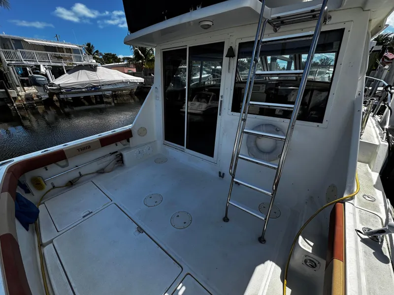 Slide: The Image of 1991 Tiara Yachts 3600 Convertible boat deck with ladder and marina view. - 2