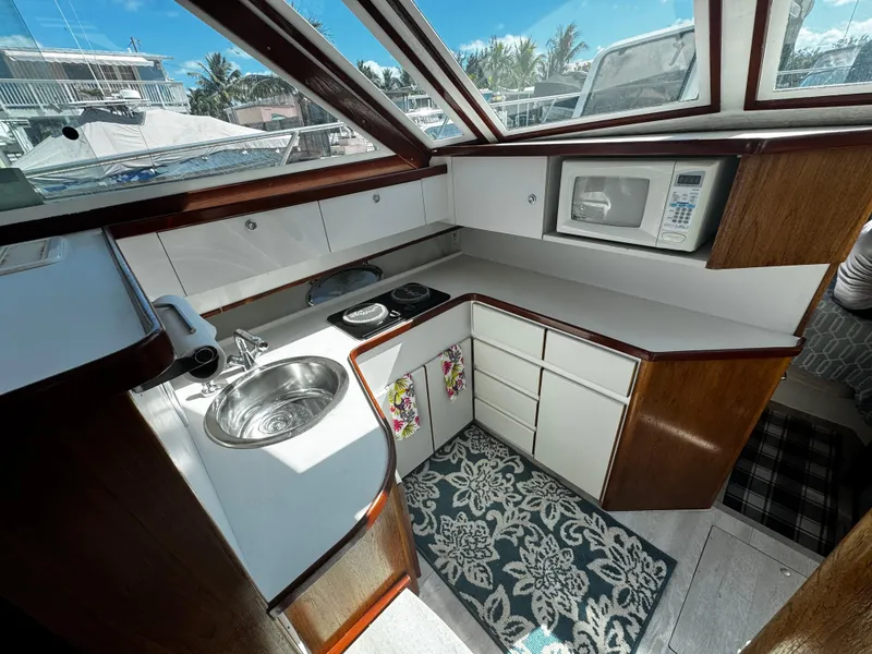 Slide: The Image of 1991 Tiara Yachts 3600 Convertible kitchen with sink, stove, microwave, and cabinets. - 28