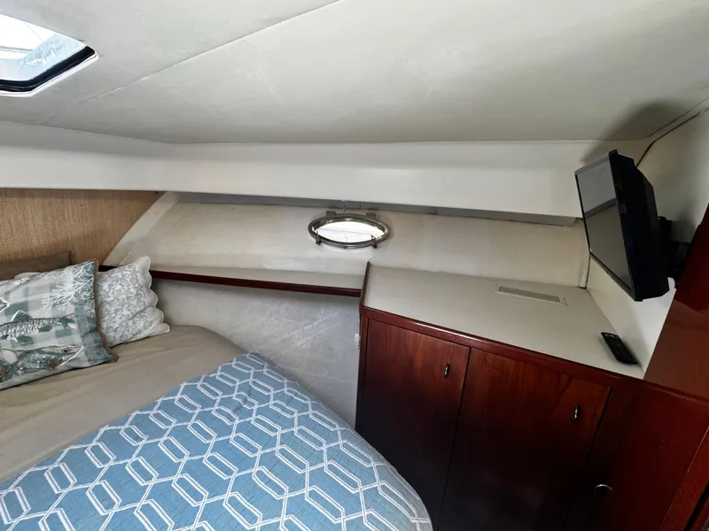 Slide: The Image of 1991 Tiara Yachts 3600 Convertible cabin with bed, TV, and wooden cabinetry. - 32