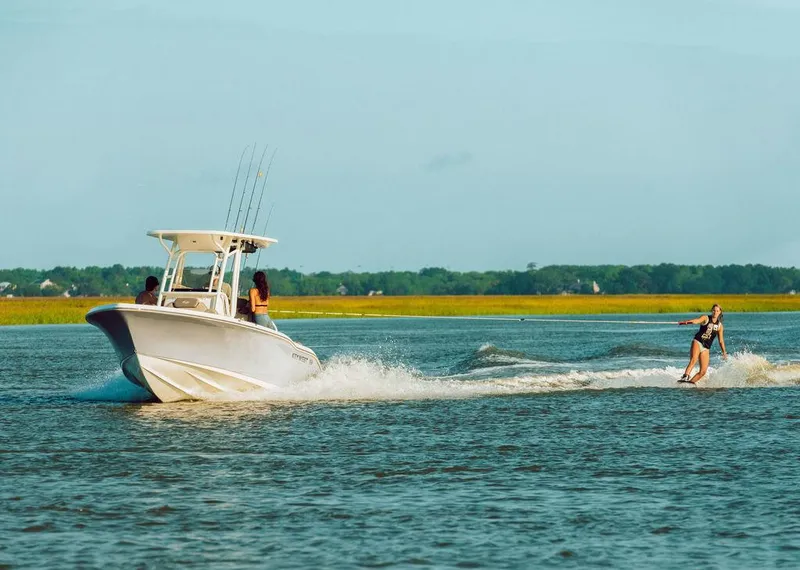 Slide: The Image of 2025 Key West 219fs boat towing a wakeboarder on a sunny day. - 19