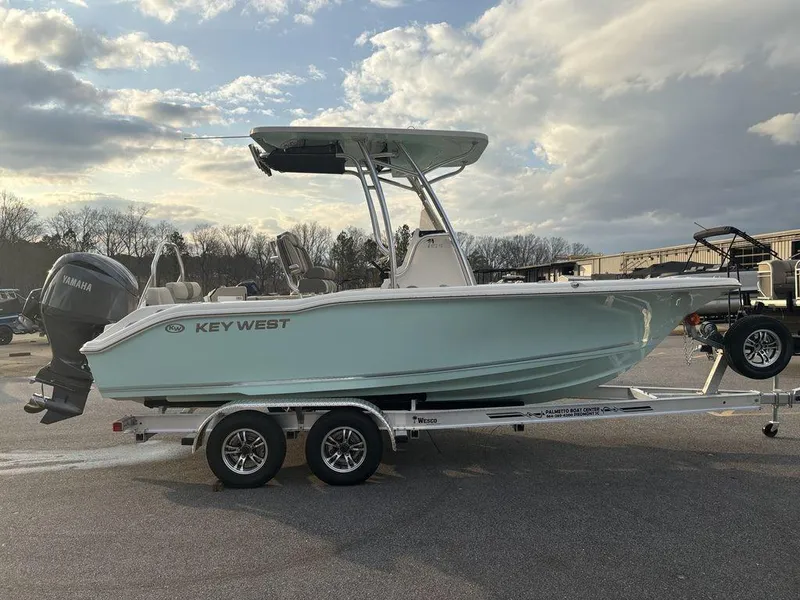Slide: The Image of 2025 Key West 219fs boat on trailer, parked outdoors under cloudy sky. - 4