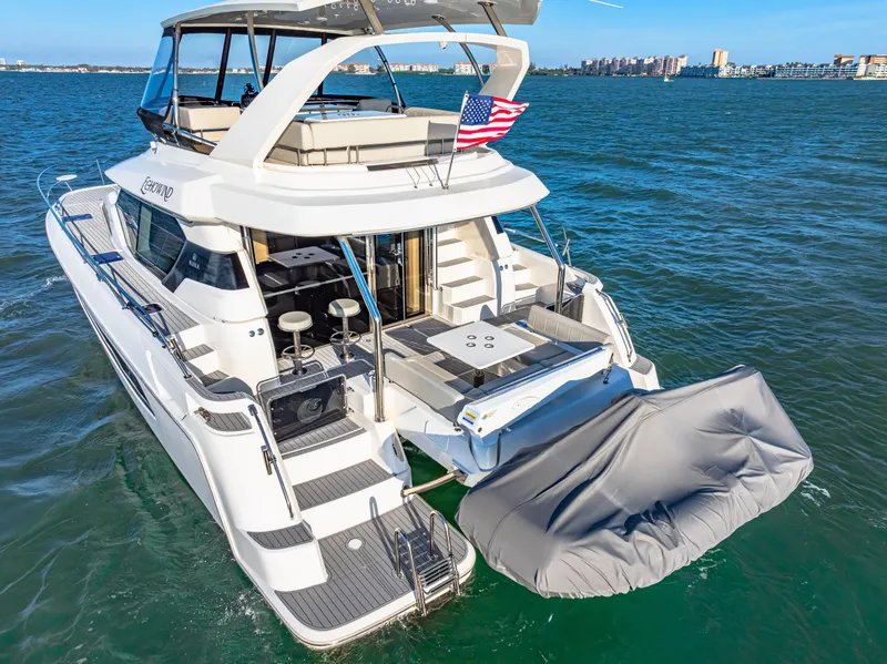 Slide: The Image of Aquila 44 Yacht 2022 cruising on open water with covered tender and American flag. - 12