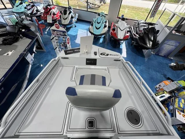 Slide: The Image of 2025 G3 Sportsman 2100 boat interior in showroom with jet skis displayed. - 10