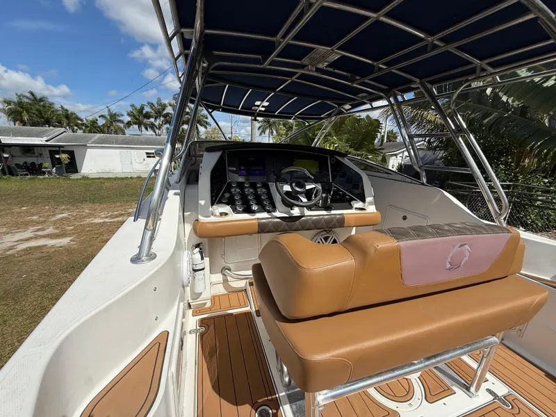 Slide: The Image of 2010 Fountain 38 LX boat cockpit with tan seating and modern controls under a canopy. - 14