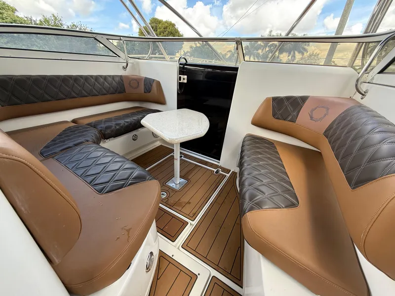 Slide: The Image of Interior of 2010 Fountain 38 LX boat with brown and black seating, wooden flooring, and a small table. - 26