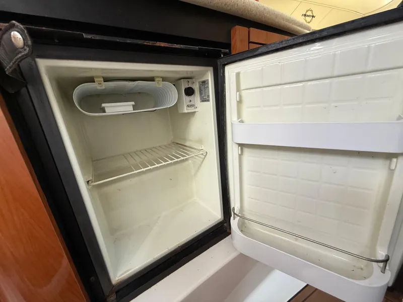 Slide: The Image of Open mini fridge inside 2010 Fountain 38 LX boat, showing empty shelves and door storage. - 30
