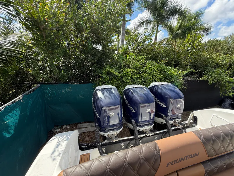 Slide: The Image of 2010 Fountain 38 LX boat with triple outboard engines, surrounded by lush greenery. - 4