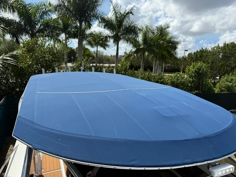 Slide: The Image of 2010 Fountain 38 LX boat with blue cover, surrounded by palm trees. - 40