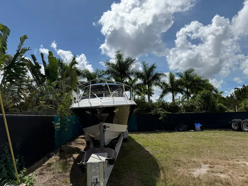 Slide: The Image of 2010 Fountain 38 LX boat on trailer, surrounded by palm trees under a partly cloudy sky. - 43