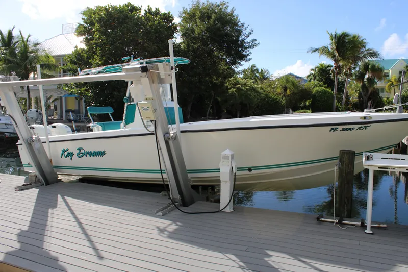 Slide: The Image of 1999 Whitewater 28 Center Console boat docked, surrounded by tropical trees and calm water. - 5