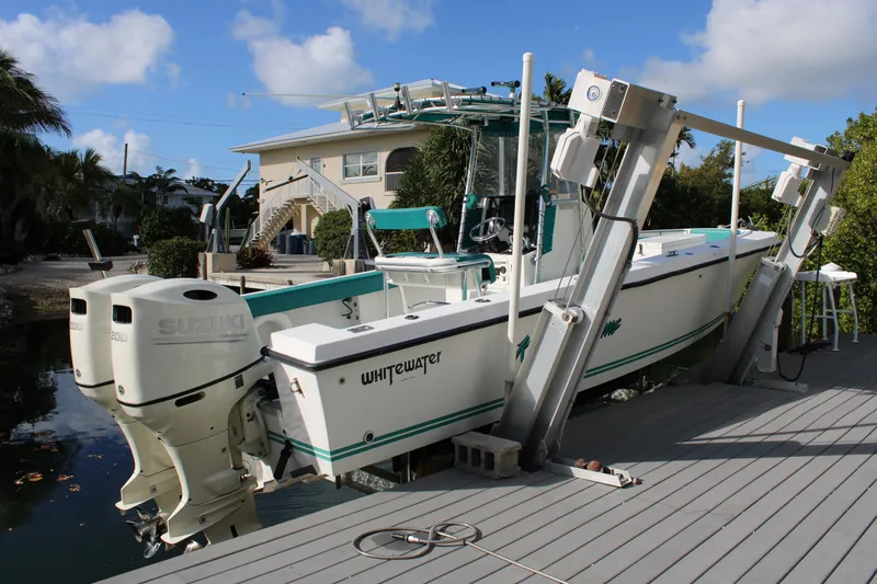 Slide: The Image of 1999 Whitewater 28 Center Console boat docked, featuring dual engines and a spacious deck. - 6
