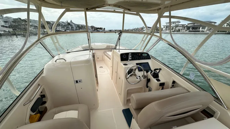 Slide: The Image of 2013 Grady-White Freedom 285 boat interior with steering wheel, dashboard, and seating on calm water. - 14