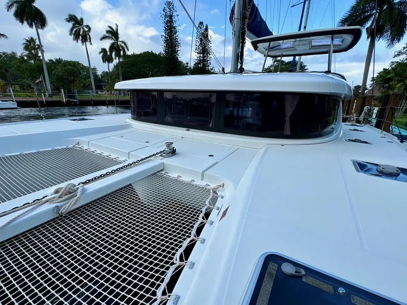 Slide: The Image of 2019 Lagoon 42 catamaran deck with netting, docked near palm trees. - 14