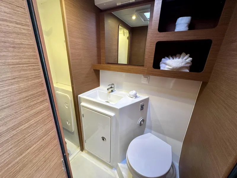 Slide: The Image of Bathroom interior of 2019 Lagoon 42 catamaran with sink, toilet, and storage shelves. - 33