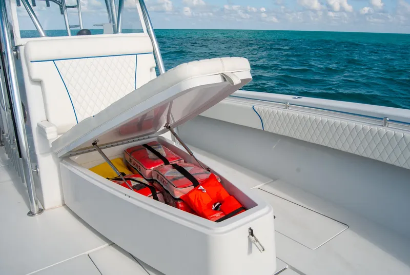 Slide: The Image of 2019 Contender 39 ST boat with open storage compartment, life jackets visible, on the ocean. - 19