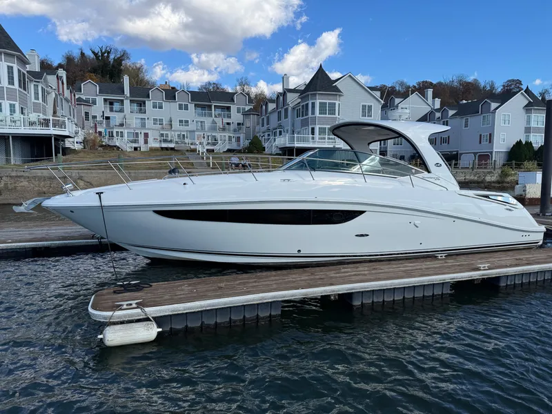 Slide: The Image of 2016 Sea Ray 370 Sundancer docked near waterfront homes under a partly cloudy sky. - 0