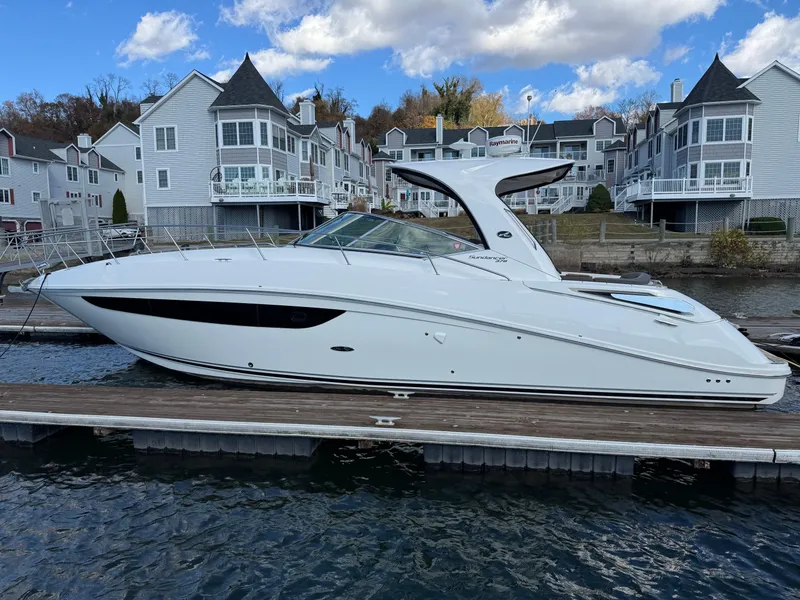 Slide: The Image of 2016 Sea Ray 370 Sundancer yacht docked near waterfront homes under a blue sky. - 1