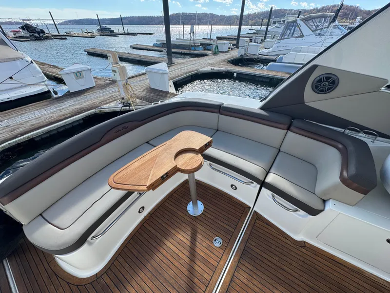 Slide: The Image of 2016 Sea Ray 370 Sundancer yacht with elegant seating and wooden table at marina. - 10