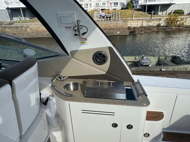 Slide: The Image of 2016 Sea Ray 370 Sundancer boat interior with kitchenette and sink by the water. - 12