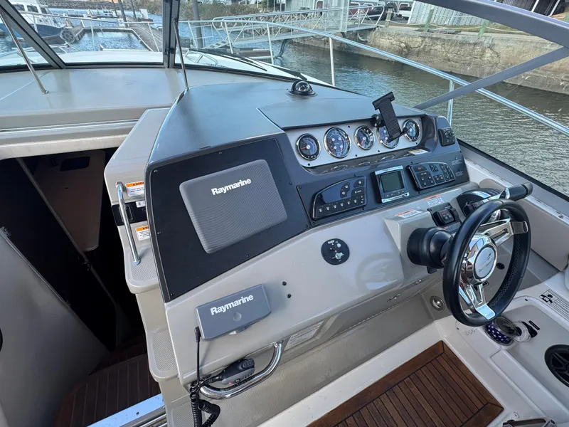 Slide: The Image of 2016 Sea Ray 370 Sundancer helm with Raymarine electronics, docked by the water. - 13