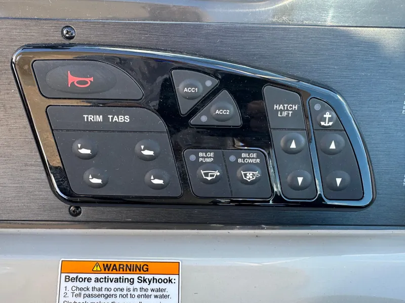 Slide: The Image of Control panel of a 2016 Sea Ray 370 Sundancer boat with various switches and warning label. - 16