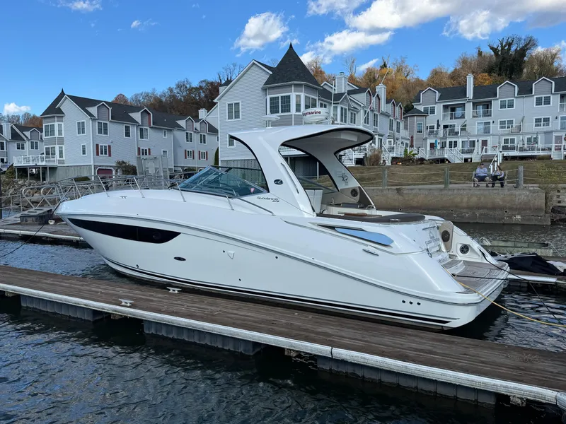 Slide: The Image of 2016 Sea Ray 370 Sundancer docked near waterfront homes under a blue sky. - 2