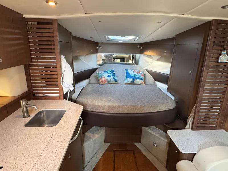Slide: The Image of 2016 Sea Ray 370 Sundancer cabin interior with bed, sink, and modern design. - 27
