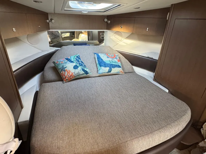 Slide: The Image of 2016 Sea Ray 370 Sundancer cabin with cozy bed and decorative pillows. - 28