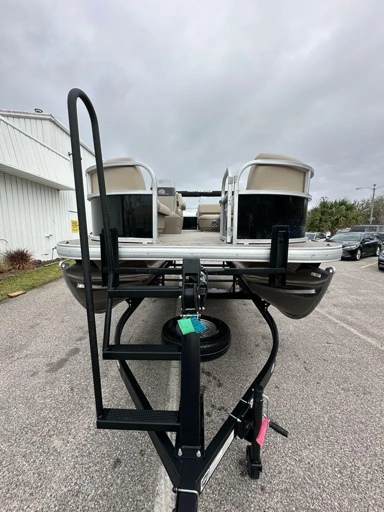 Slide: The Image of 2025 Sun Tracker Party Barge 16 DLX on trailer, parked outdoors, overcast sky. - 3