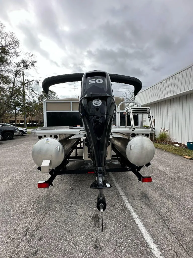 Slide: The Image of 2025 Sun Tracker Party Barge 16 DLX pontoon boat, rear view, parked outdoors. - 4