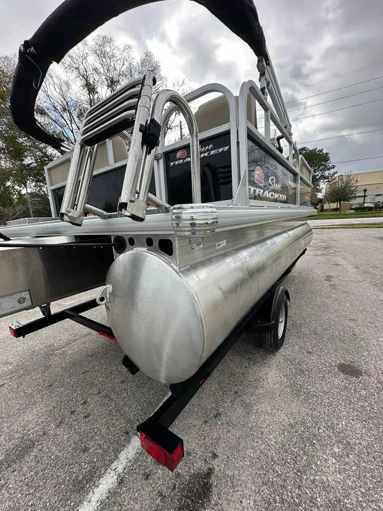 Slide: The Image of 2025 Sun Tracker Party Barge 16 DLX pontoon boat on a trailer, overcast sky. - 6