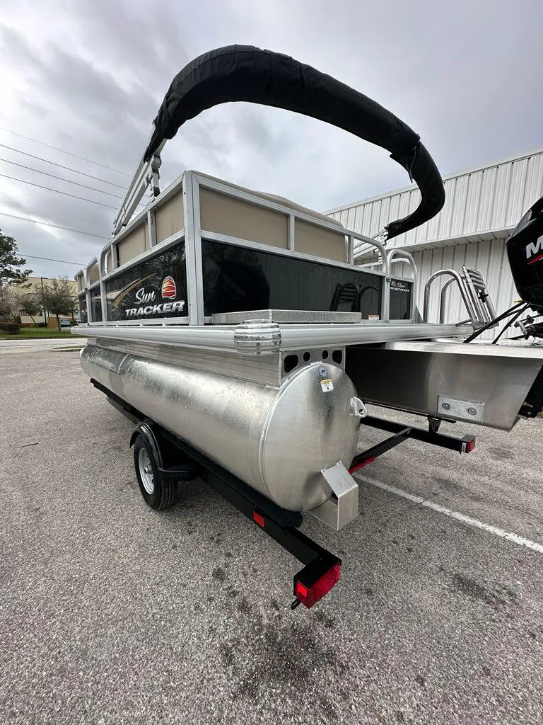Slide: The Image of 2025 Sun Tracker Party Barge 16 DLX pontoon boat on trailer, outdoor setting. - 8