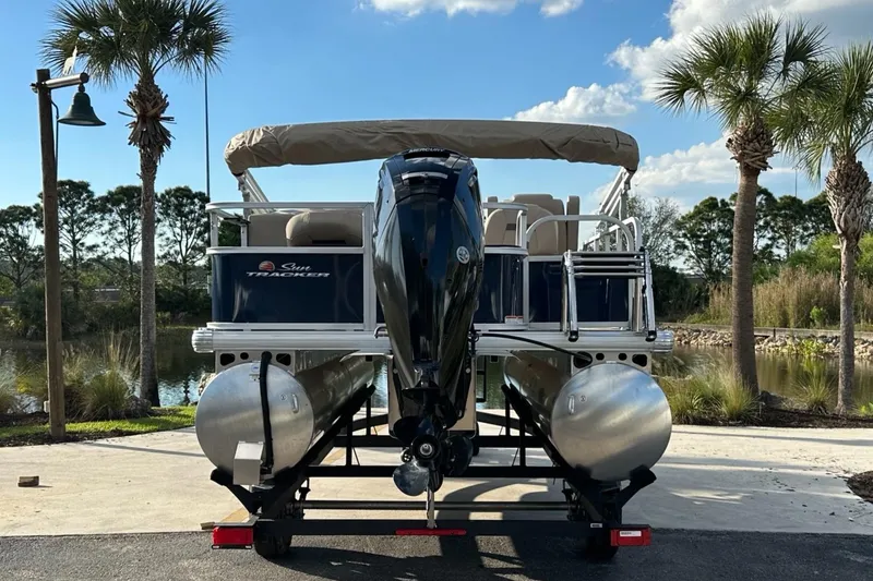 Slide: The Image of 2025 Sun Tracker Bass Buggy 18 DLX pontoon boat on trailer, scenic background. - 3