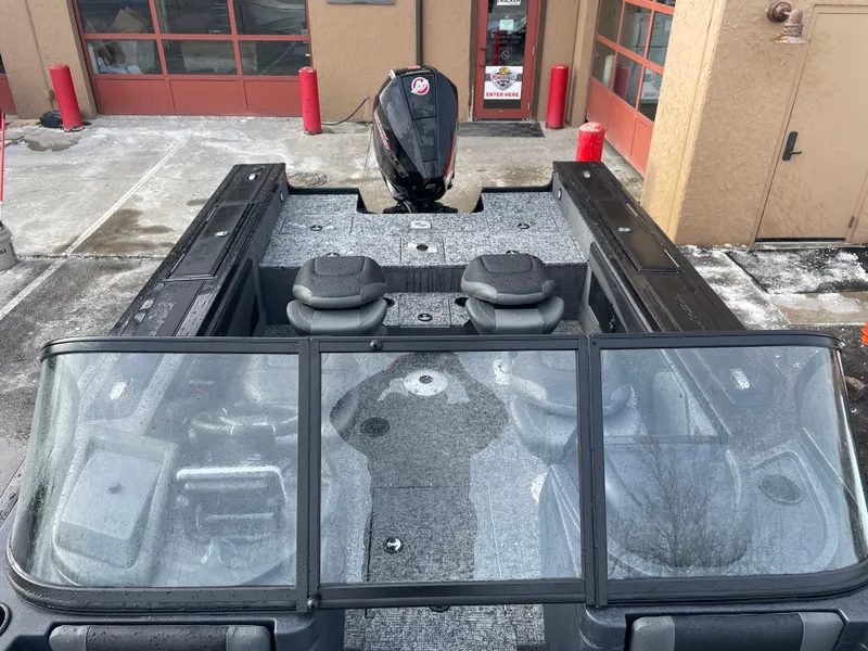 Slide: The Image of 2025 Tracker Targa V-19 WT boat with dual seats and windshield, parked outside a building. - 6