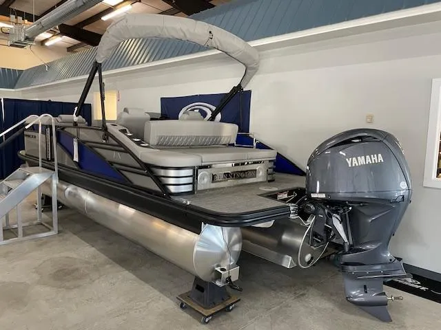 Slide: The Image of 2024 Bennington 23 LXSSB pontoon boat with Yamaha outboard motor in showroom. - 2