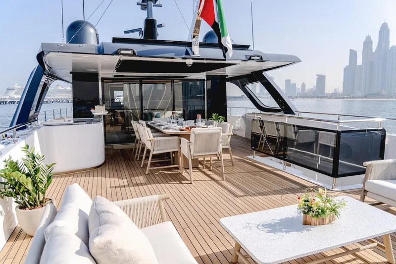 Slide: The Image of Luxurious Majesty 100 Terrace yacht deck with elegant seating, dining area, and city skyline view. - 20