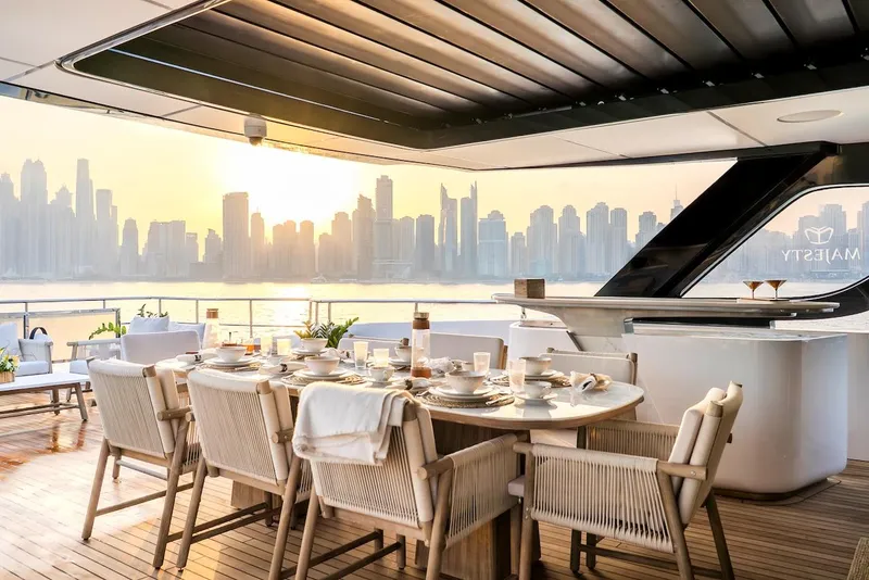 Slide: The Image of Luxurious 2025 Majesty 100 Terrace yacht with elegant dining setup and city skyline view. - 22