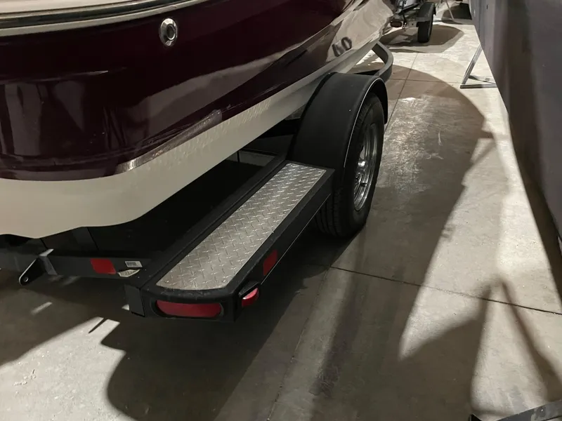 Slide: The Image of 2021 Tahoe 550 TS boat trailer with diamond plate step in a garage setting. - 2