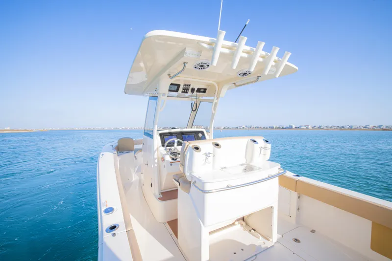 Slide: The Image of 2021 Scout 277 LXF boat on clear blue water, showcasing helm and seating area. - 21