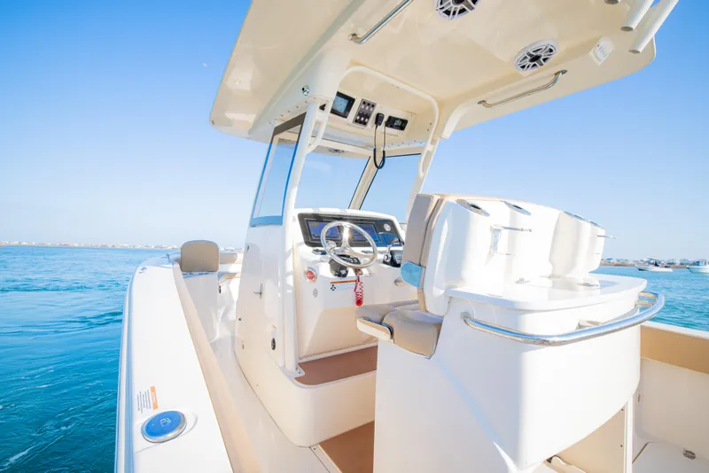 Slide: The Image of 2021 Scout 277 LXF boat interior with steering wheel, ocean backdrop. - 23