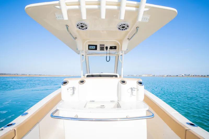 Slide: The Image of 2021 Scout 277 LXF boat on clear blue water, showcasing helm and seating area. - 24