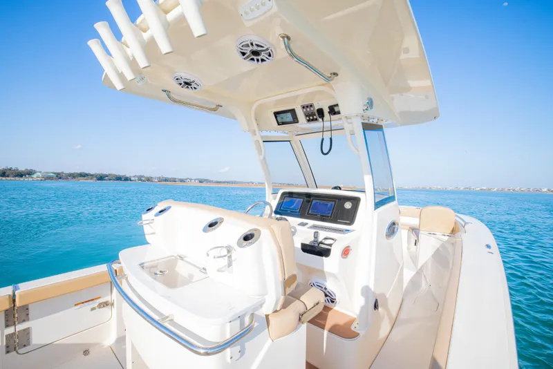 Slide: The Image of 2021 Scout 277 LXF boat interior with helm, ocean view, and clear blue sky. - 25