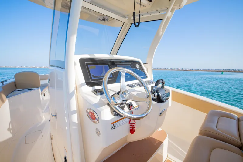 Slide: The Image of 2021 Scout 277 LXF boat helm with steering wheel, ocean view, and modern controls. - 29